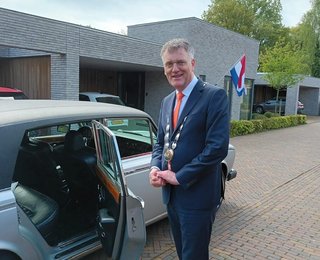 Burgemeester Hans Janssen bij auto voor lintjesregen