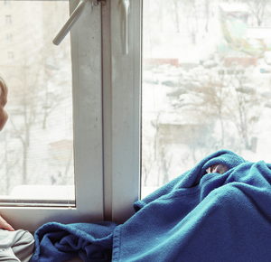 Twee kinderen voor het raam met een dekentje