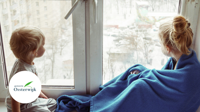 Twee kinderen voor het raam met een dekentje