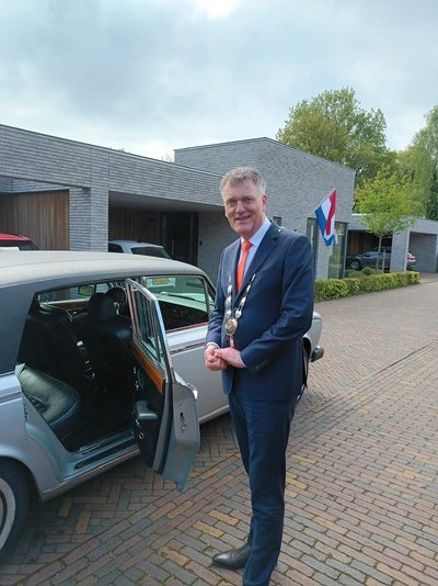 Burgemeester Hans Janssen bij auto voor lintjesregen