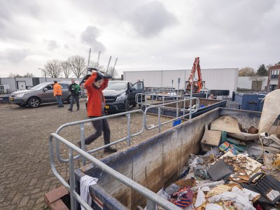 medewerker milieustraat gooit afval weg