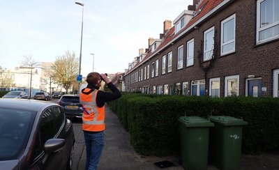 man in oranje hesje maakt foto van huizen