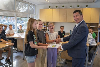 Drie kinderen en wethouder Eric Logister, krijgt een rapport overhandigd