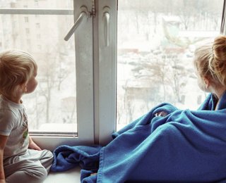 Twee kinderen voor het raam met een dekentje