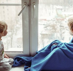 Twee kinderen voor het raam met een dekentje