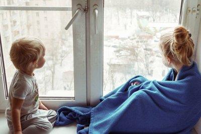 Twee kinderen voor het raam met een dekentje