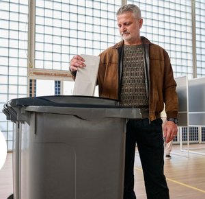 Man stopt stembiljet in de stemcontainer